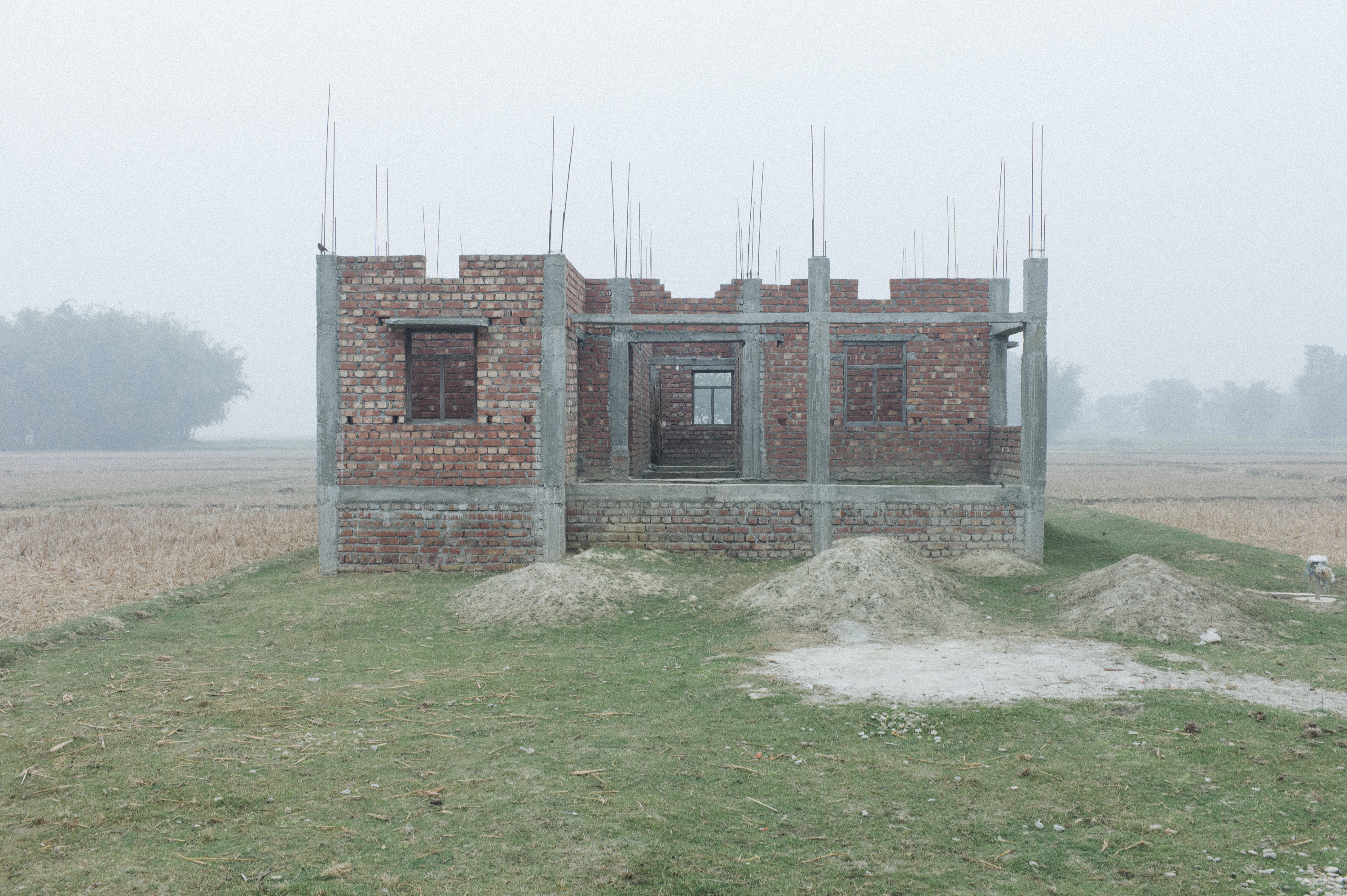 Ein unfertiger Ziegelrohbau in einer nebeligen Landschaft