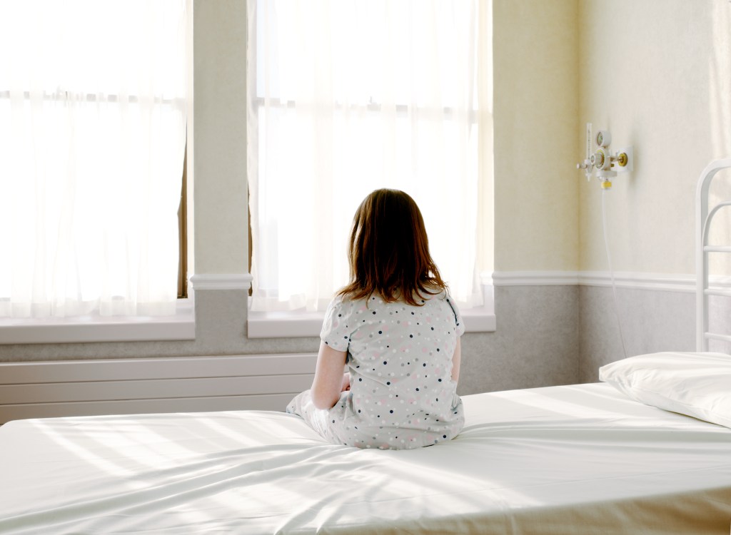 Girl sits on hospital bed (getty)