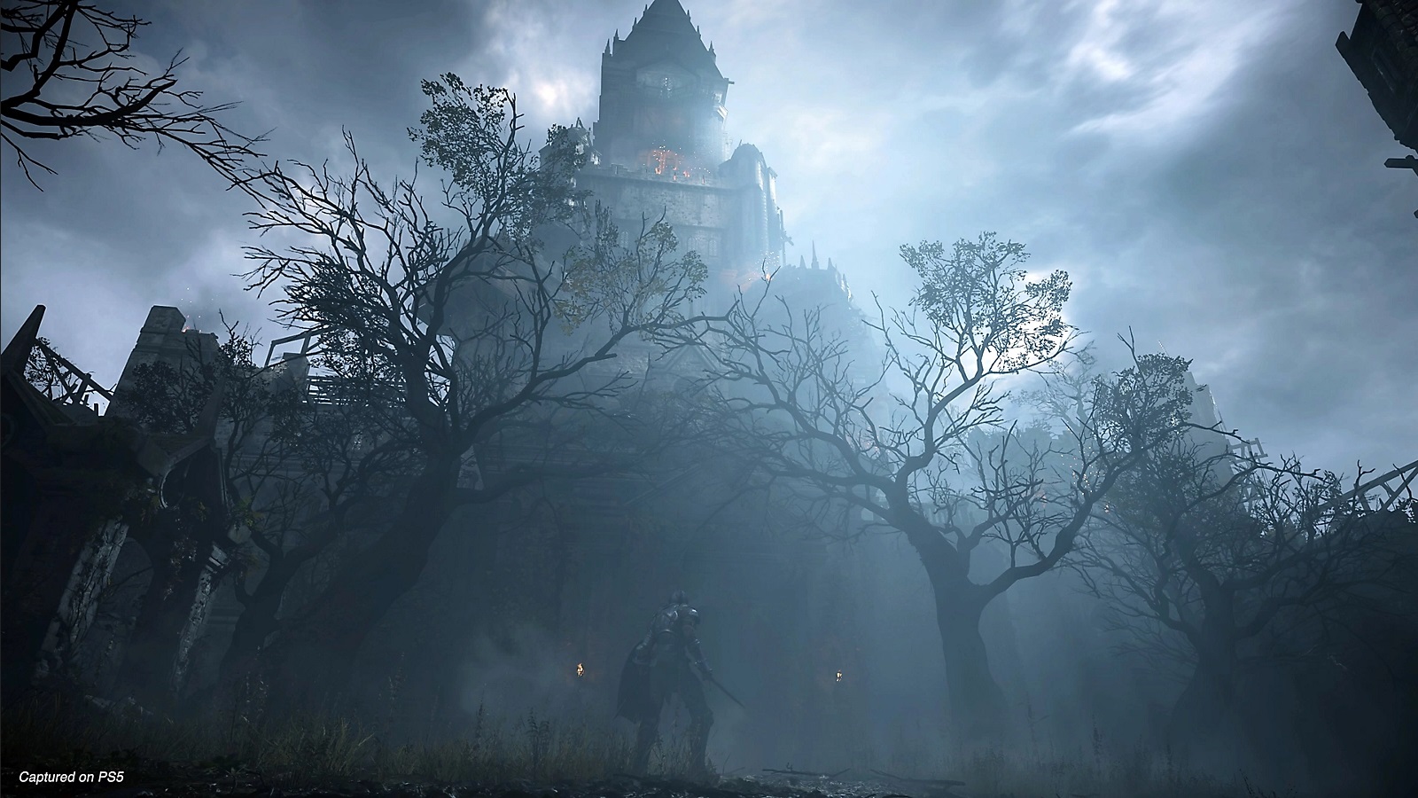 A moonlit tower soars above the trees and looms over a small player character as they approach.