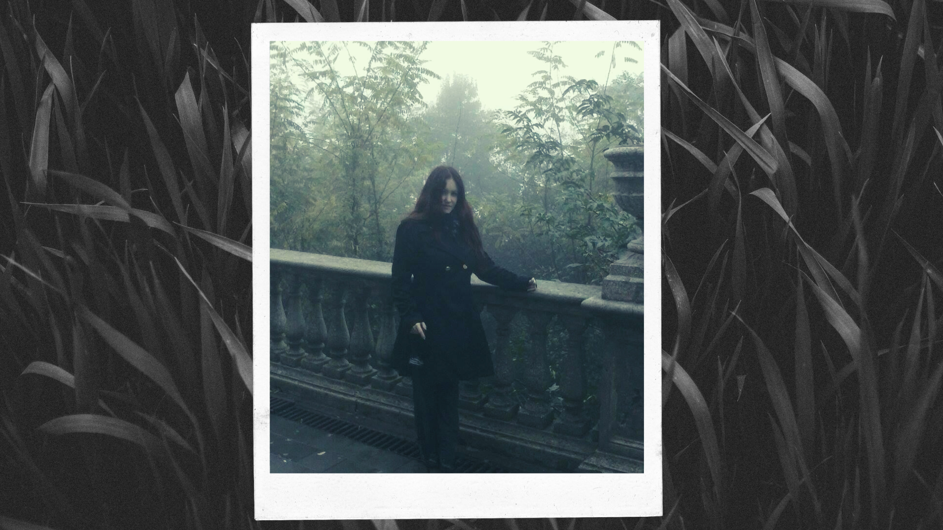 Jennifer Mazzetta Crepuscolo, Unione Satanisti Italiani – Photo of a young woman with long red hair, wearing a black coat and black pants and posing on a historical balcony overlooking a park.