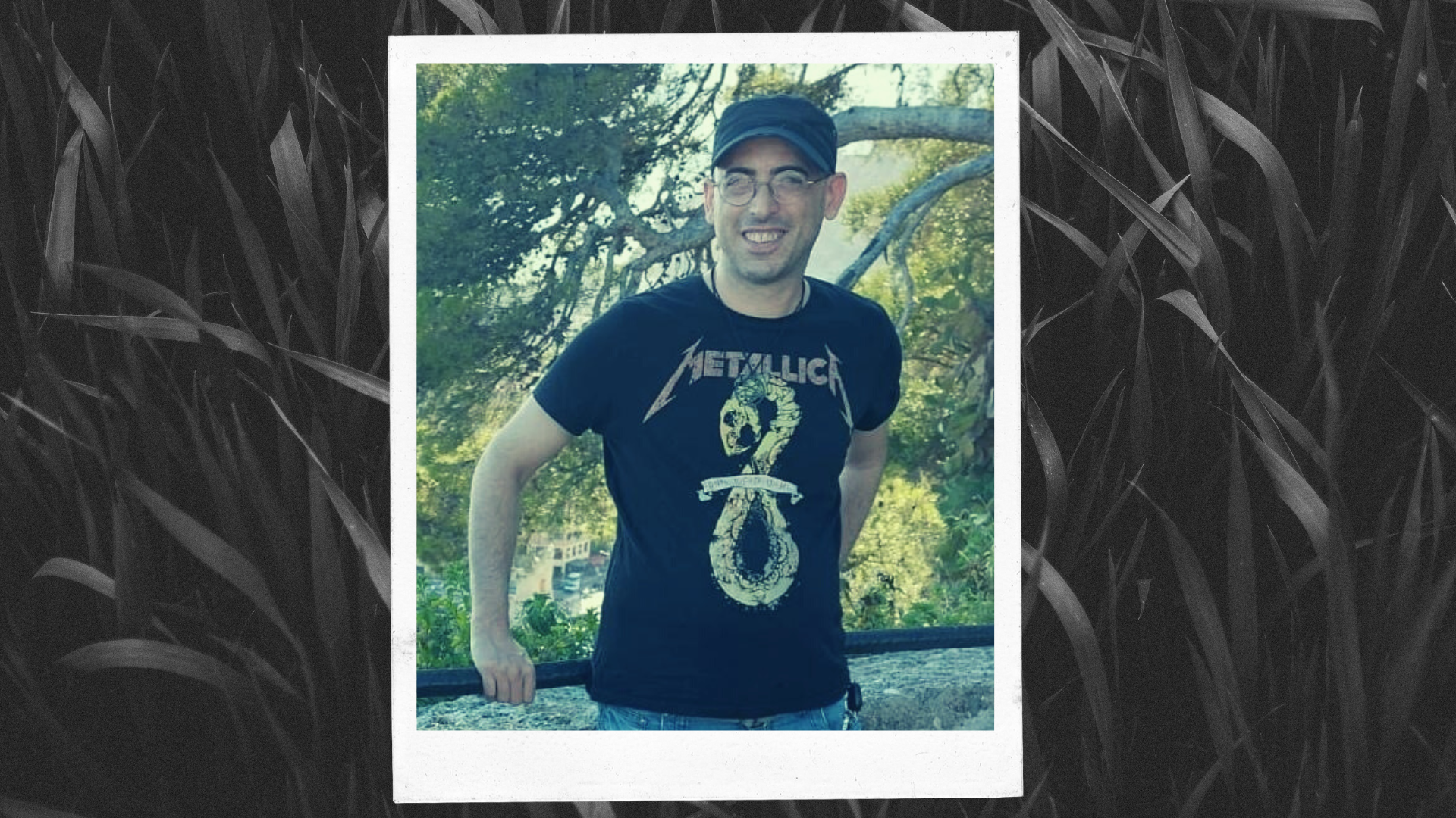 Davide, Unione Satanisti Italiani – photo of a man wearing a black cap, a metallica t-shirt and round glasses, posing in nature.