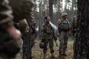 Jan Schneidereit, EOD diffusion team Ukraine – a group of people in military gear standing in the woods. One of them is smoking a cigarette.