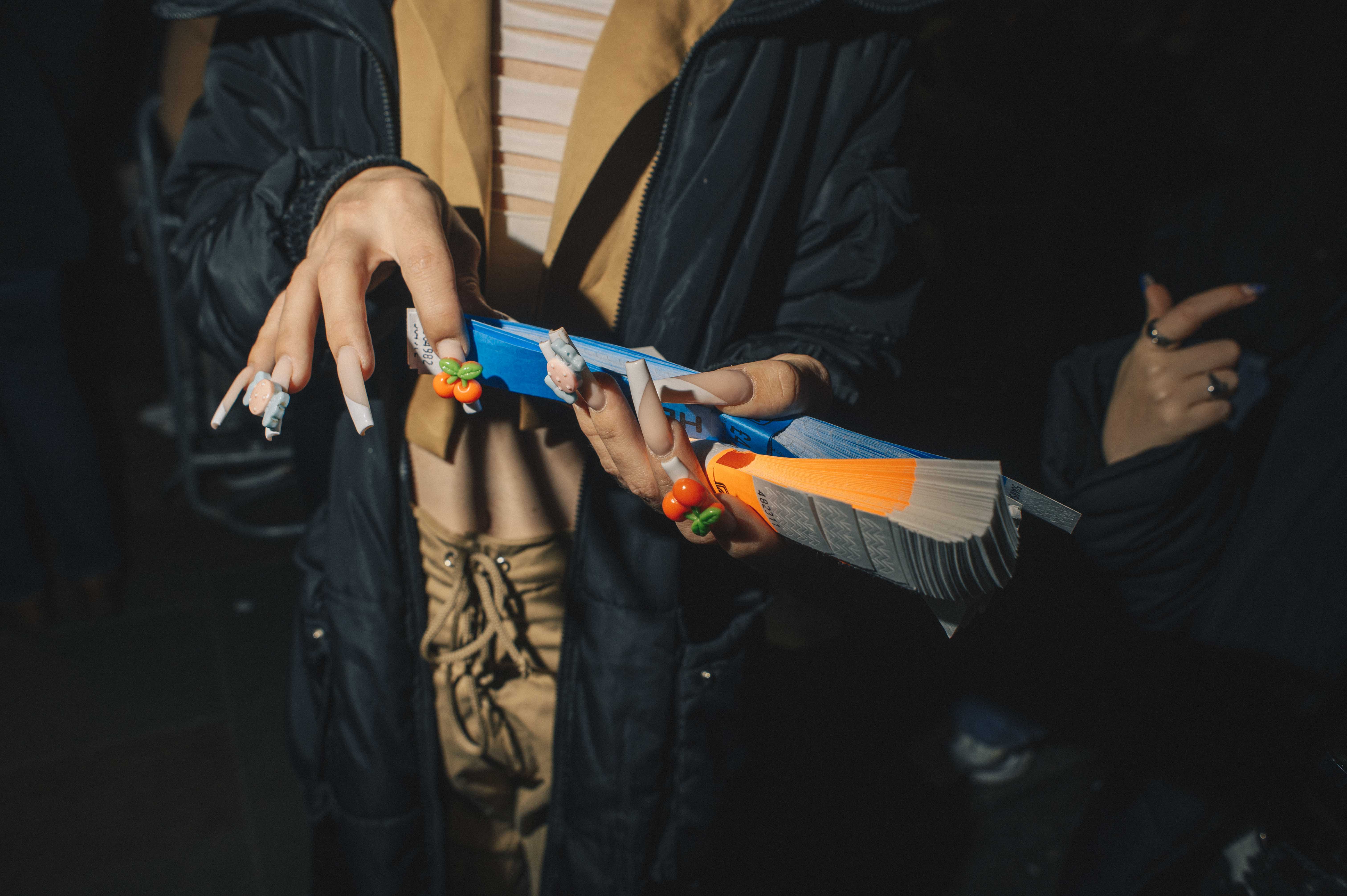 A detail shot of woman with long gel nails handing out paper wristbands.