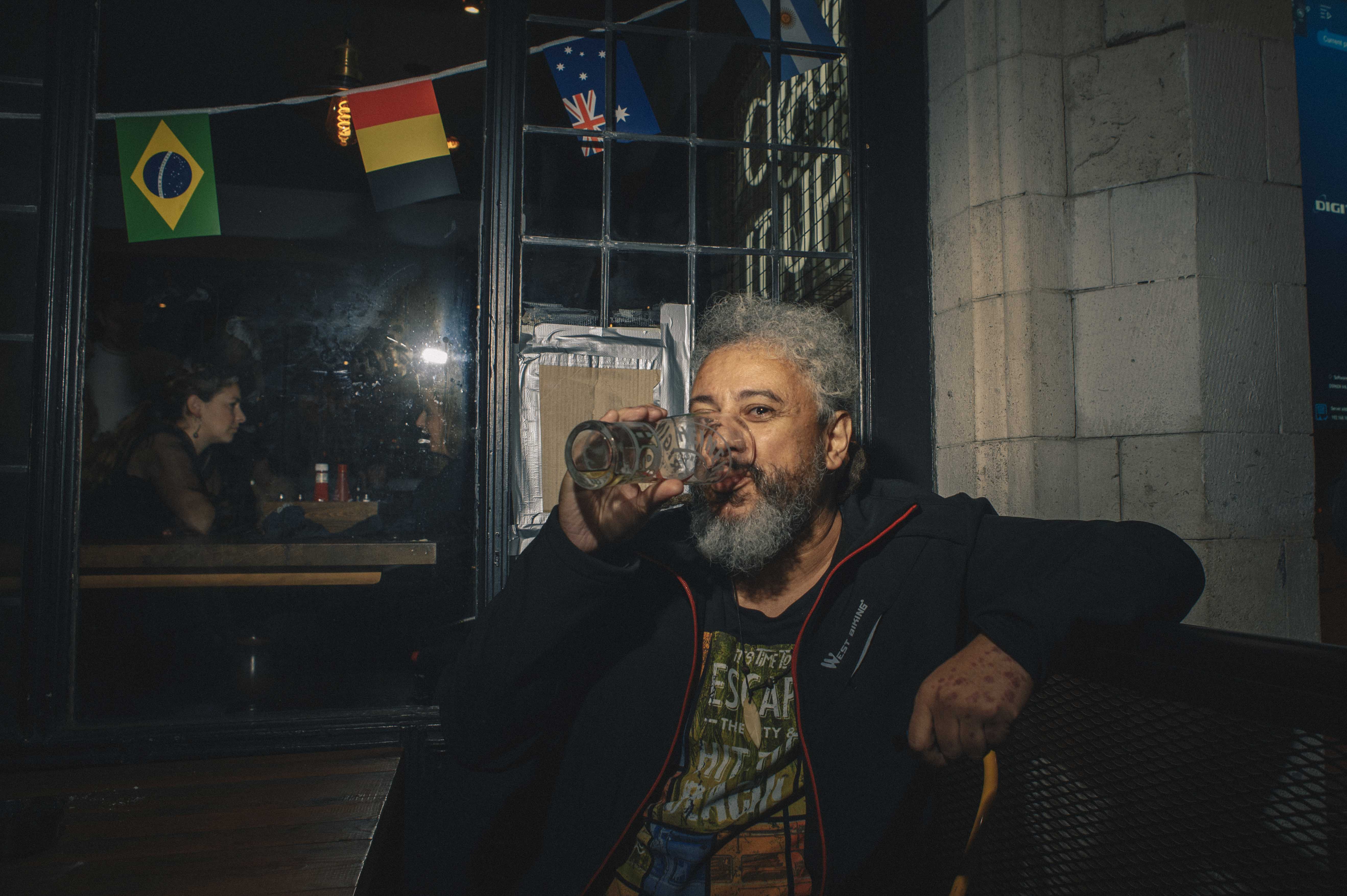 An older man drinks a pint of beer in a pub