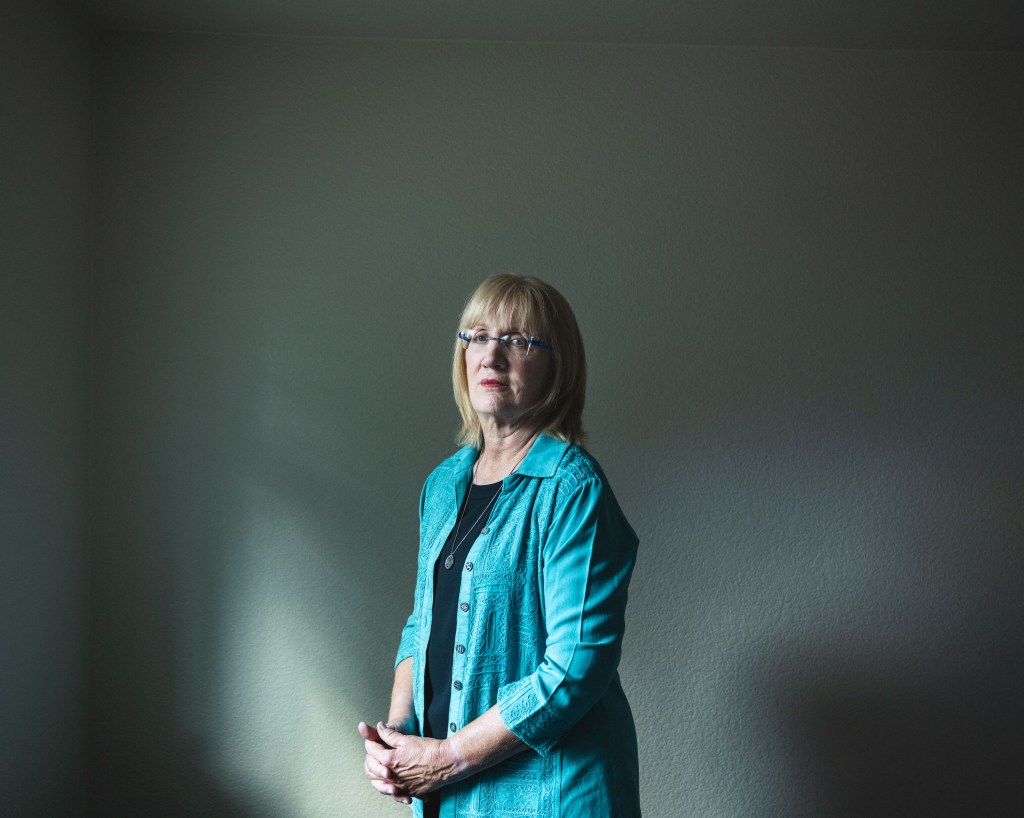 Christa Brown in her home against a white wall.