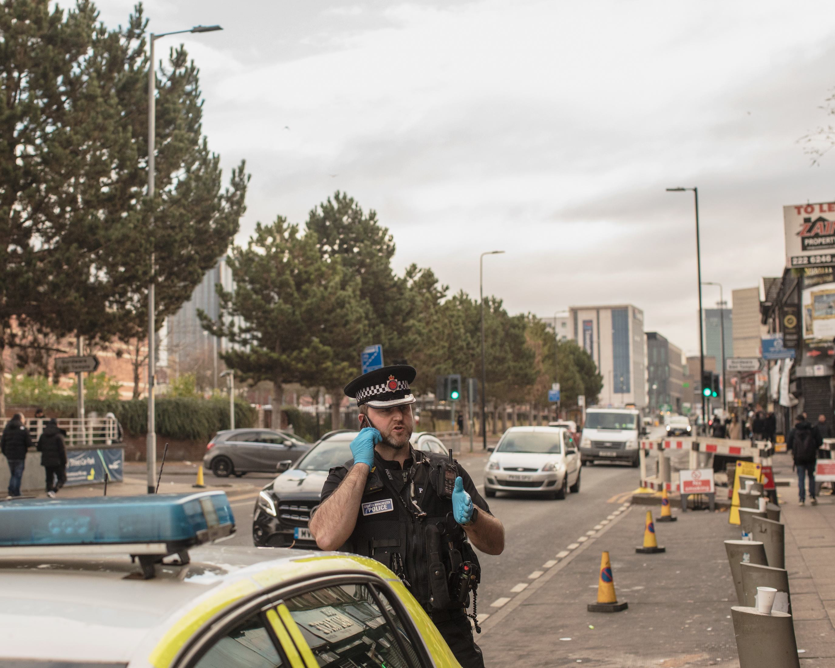 A police officer is talking on the phone standing near a police vehicle.