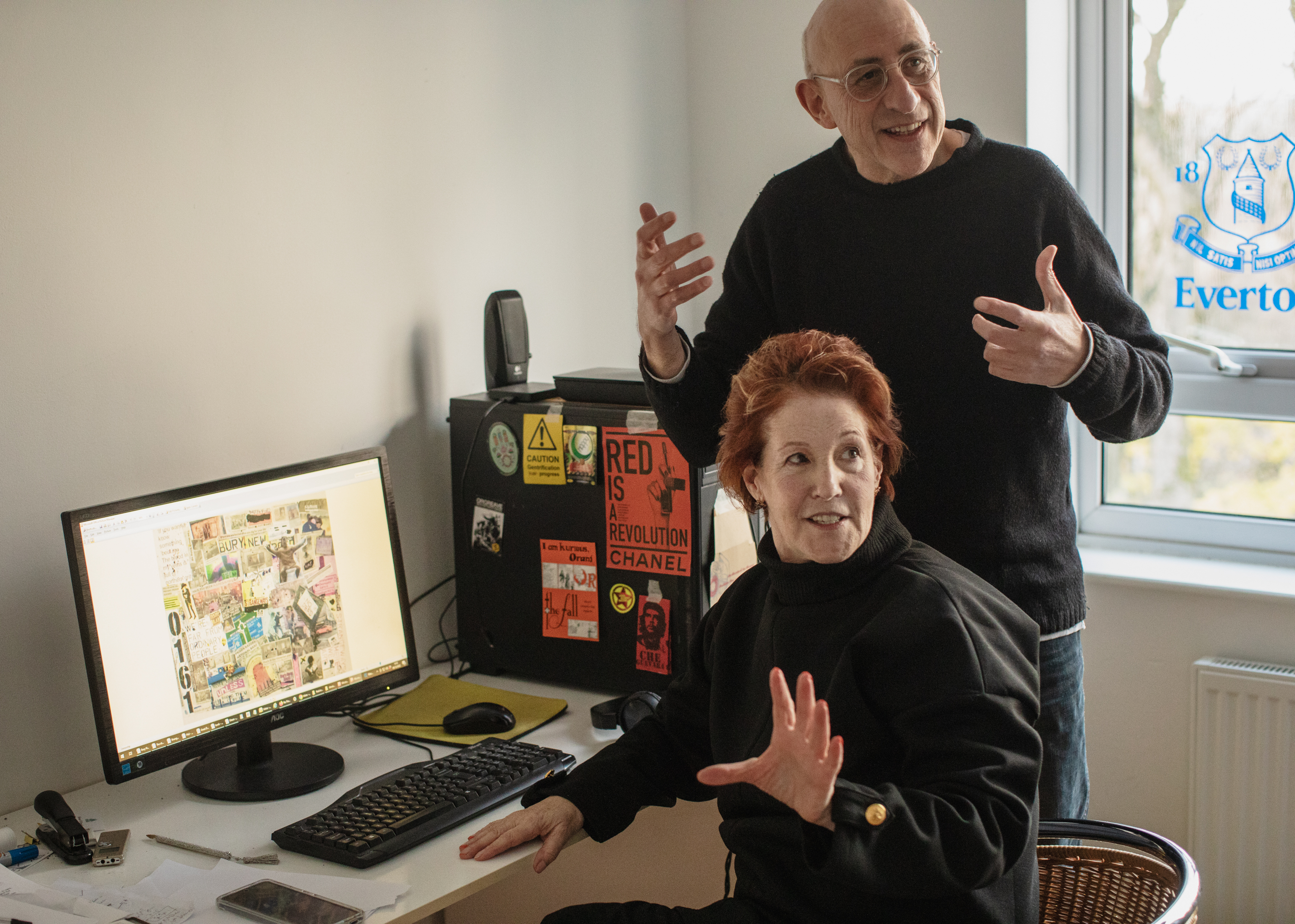 Sandra Bouguerch and Stephen Kingston gesturing away from the camera while sitting at a desk with a computer. The computer screen shows an artwork.