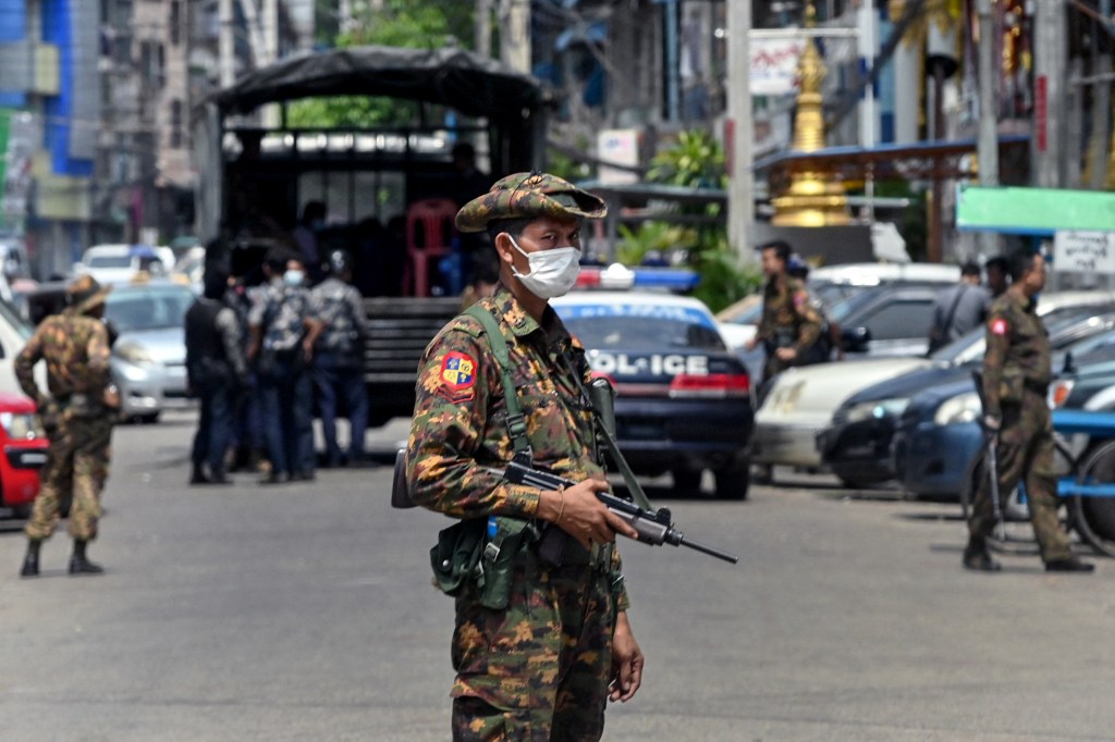 A soldier stands guard along a road as security forces search for protesters, who had been taking part in a demonstration against the military coup, in Yangon