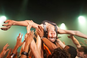 A woman crowd surfing while arms hold he