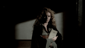 Still from Nostalghia, a woman half in shadow and half in light ho