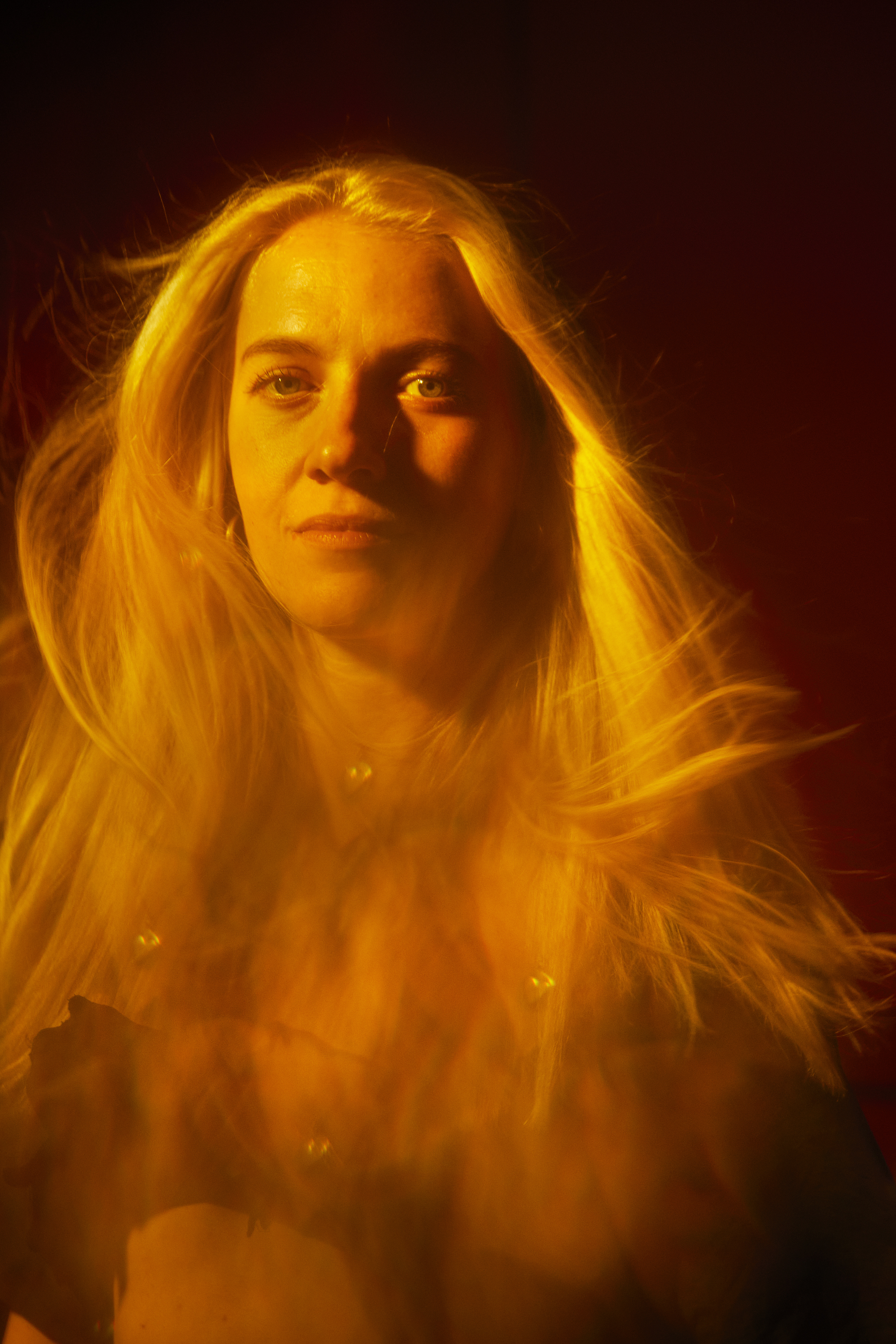 Isabel - blurry portrait of a blond woman with light eyes in orange light