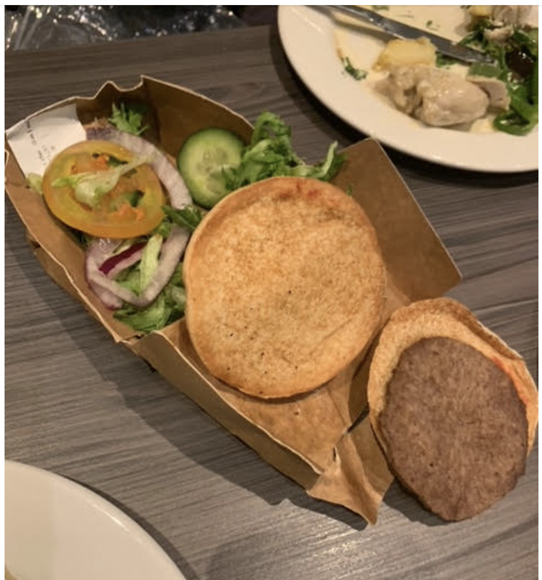 A photo of a rather grim looking burger and pile of salad.