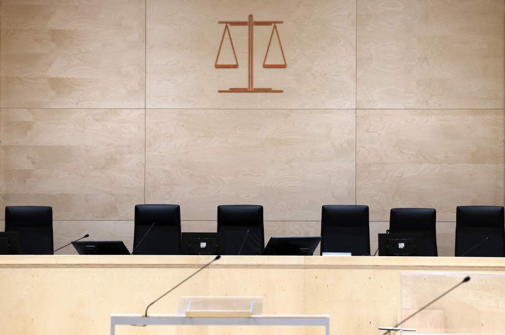 A courtroom with black chairs and scales of justice logo on the wall