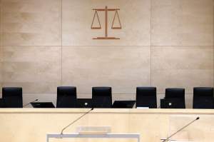 A courtroom with black chairs and scales of justice logo on the wall