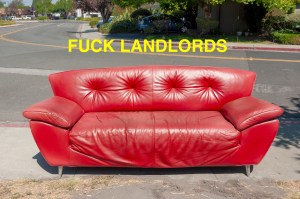 Abandoned red couch on the street with 'eff landlords' message