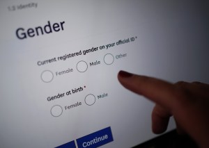 ​A finger pointing at a computer screen with a prompt to select gender