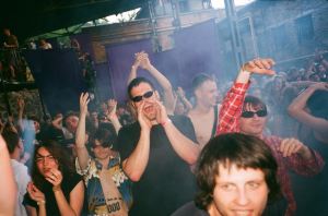 BRUDNIY PES Ukraine party – photo of a crowd of people dancing and shouting outside, surrounded by clouds of smoke.