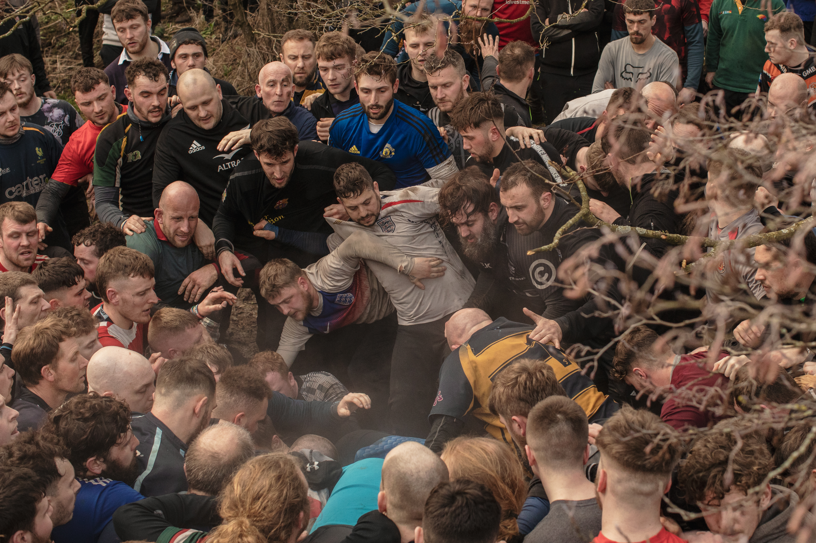 Dozens of men fill the frame as they fight over an unseen ball.