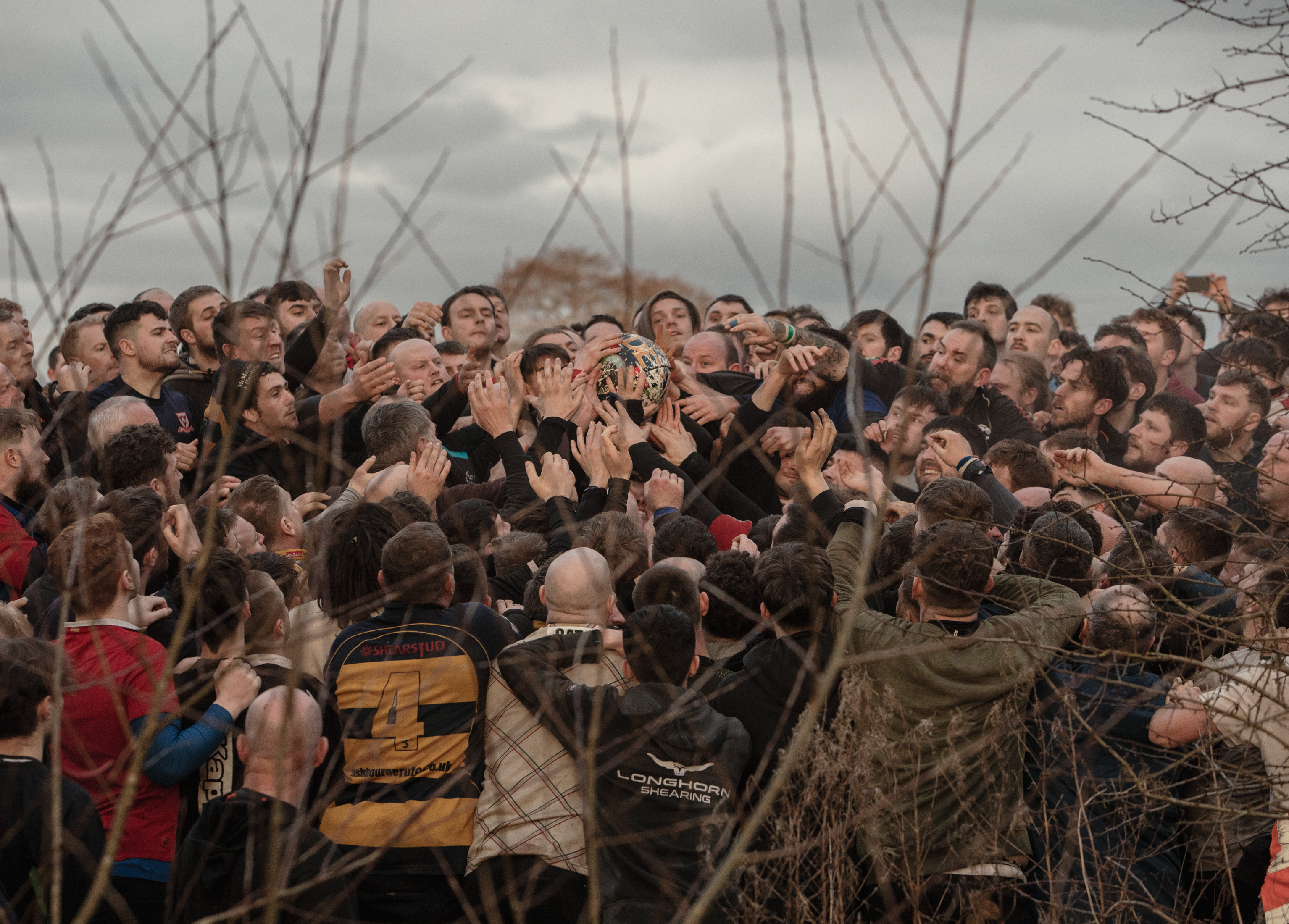 Dozens of men reach for a ball.