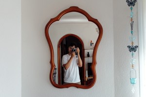 Young man taking a self portrait in a mirror with a vintage camera