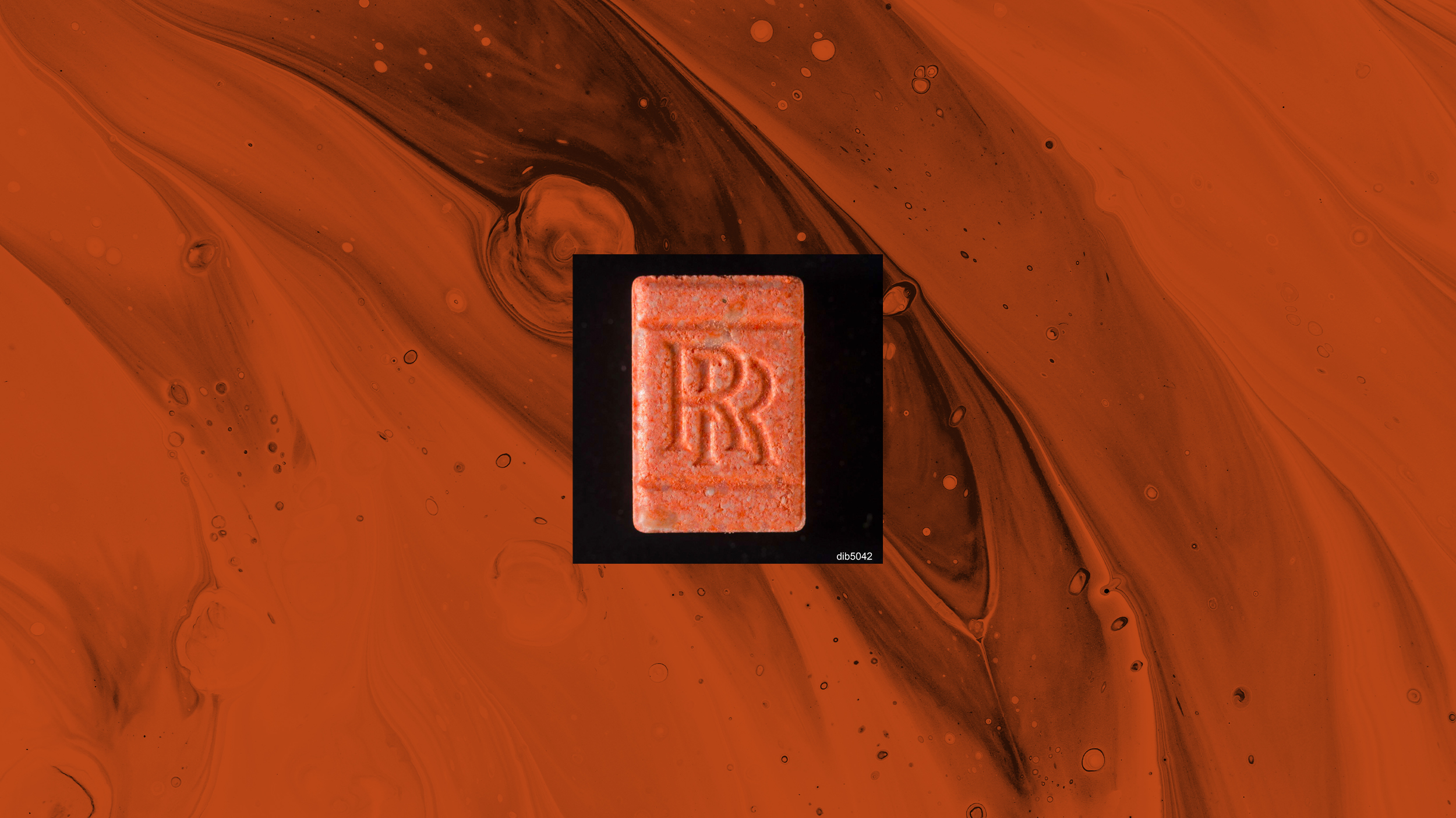 Eine orange Pille mit Rolls Royce Logo vor orangem Hintergrund