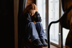 Upset girl sitting in window.