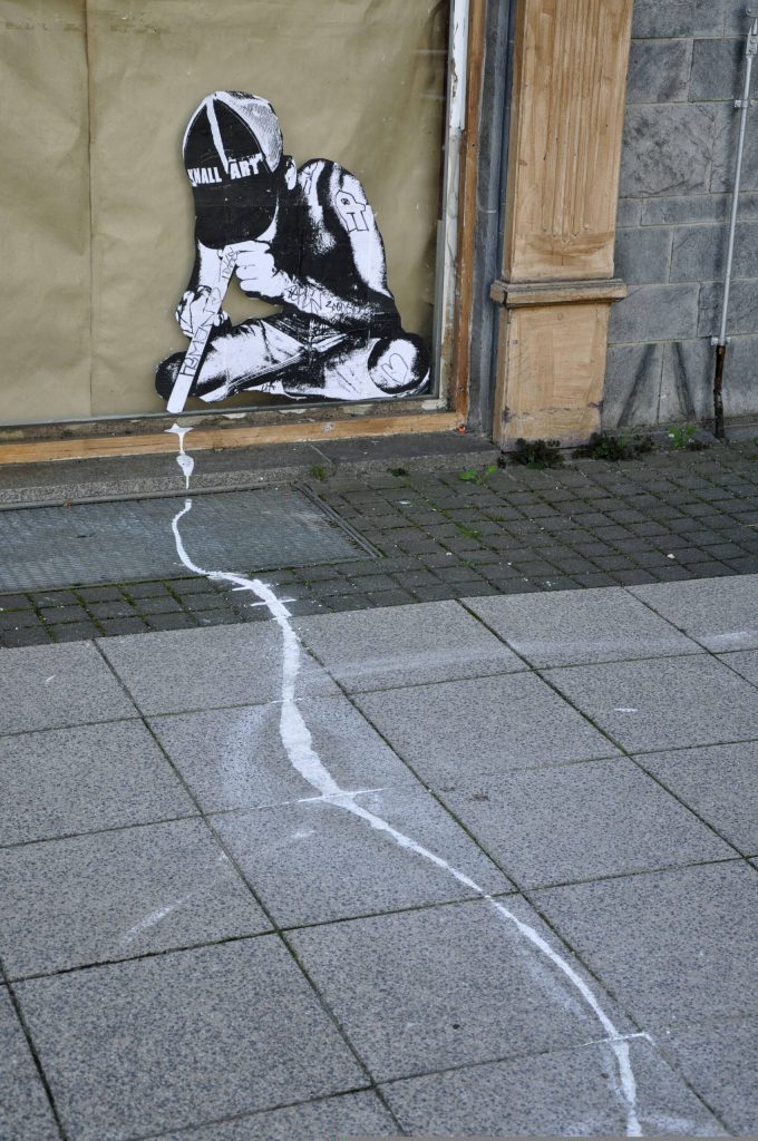 Streetart an einer Schaufensterscheibe, die eine junge Person zeigt, die eine weiße Linie am Gehsteig durch die Nase zieht