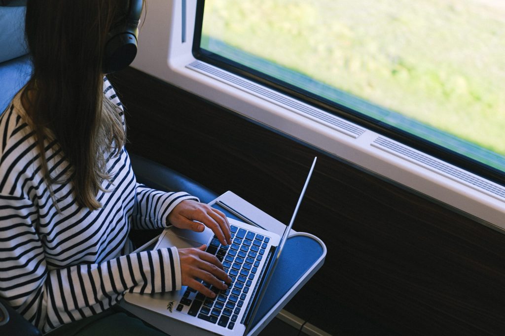 Foto ilustrasi perempuan pakai headset saat membuka laptop