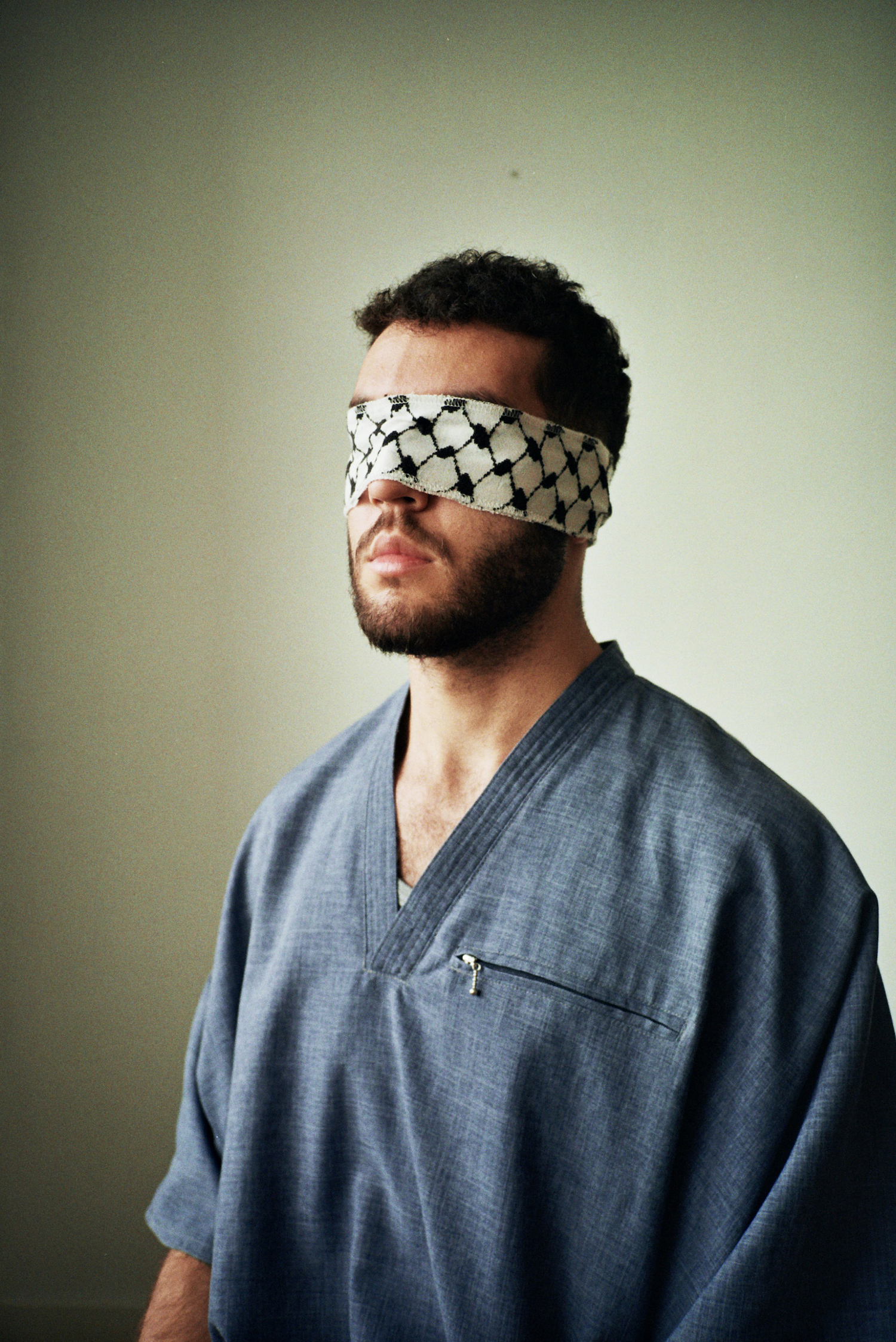 Ramadan photos. A man wearing a blue jellaba and a piece of keffiyeh fabric in front of his eyes.