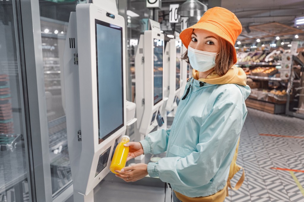 A photo of a girl wearing  scanning a juice at a supermarket.