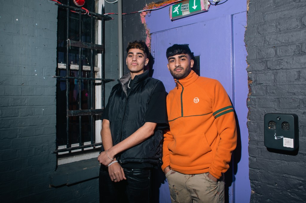 Twee jonge mannen staan tegen de muur van een gebouw