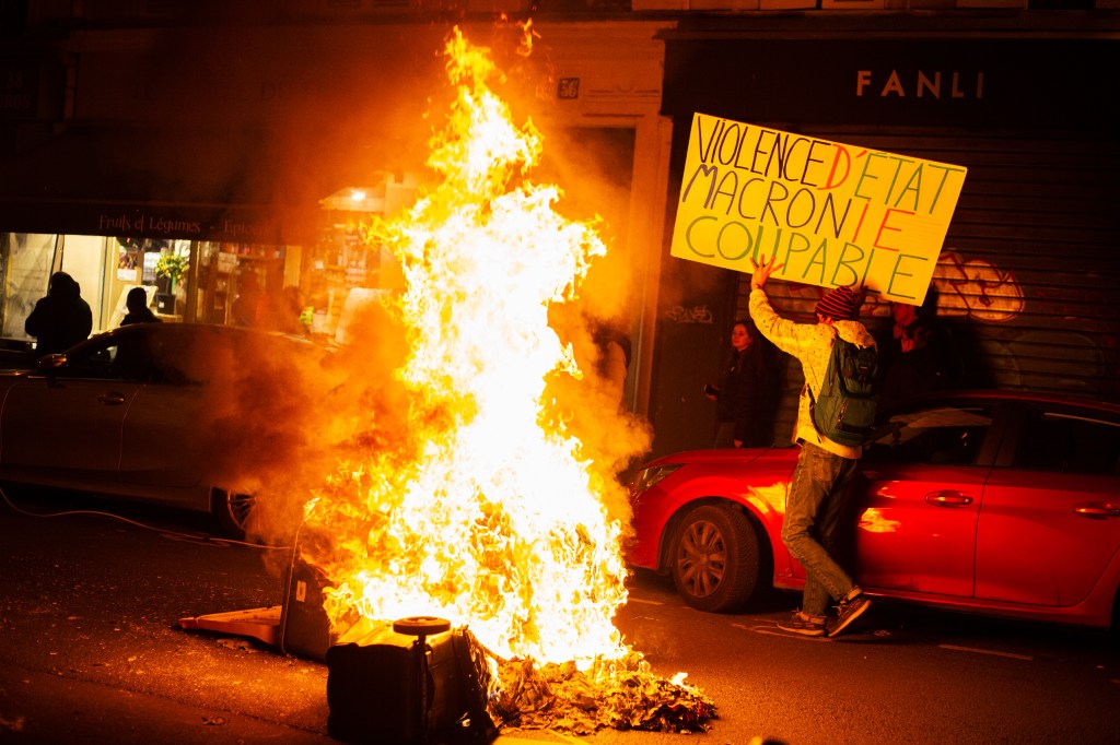 french protestor walks next to fire