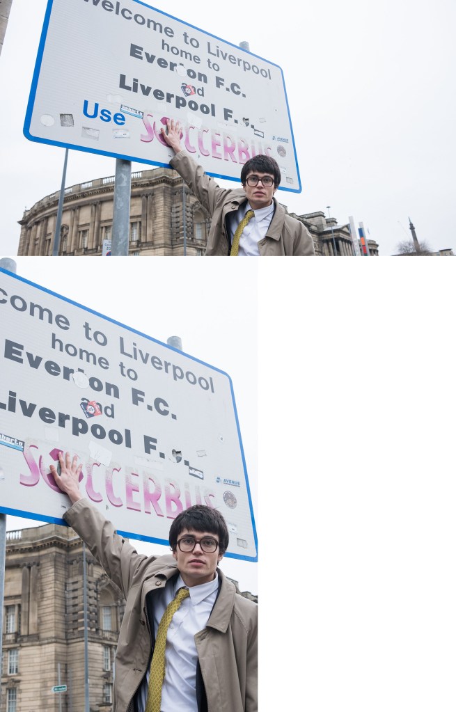 Liverpool, England: A man in a trench coat pointing to city sign