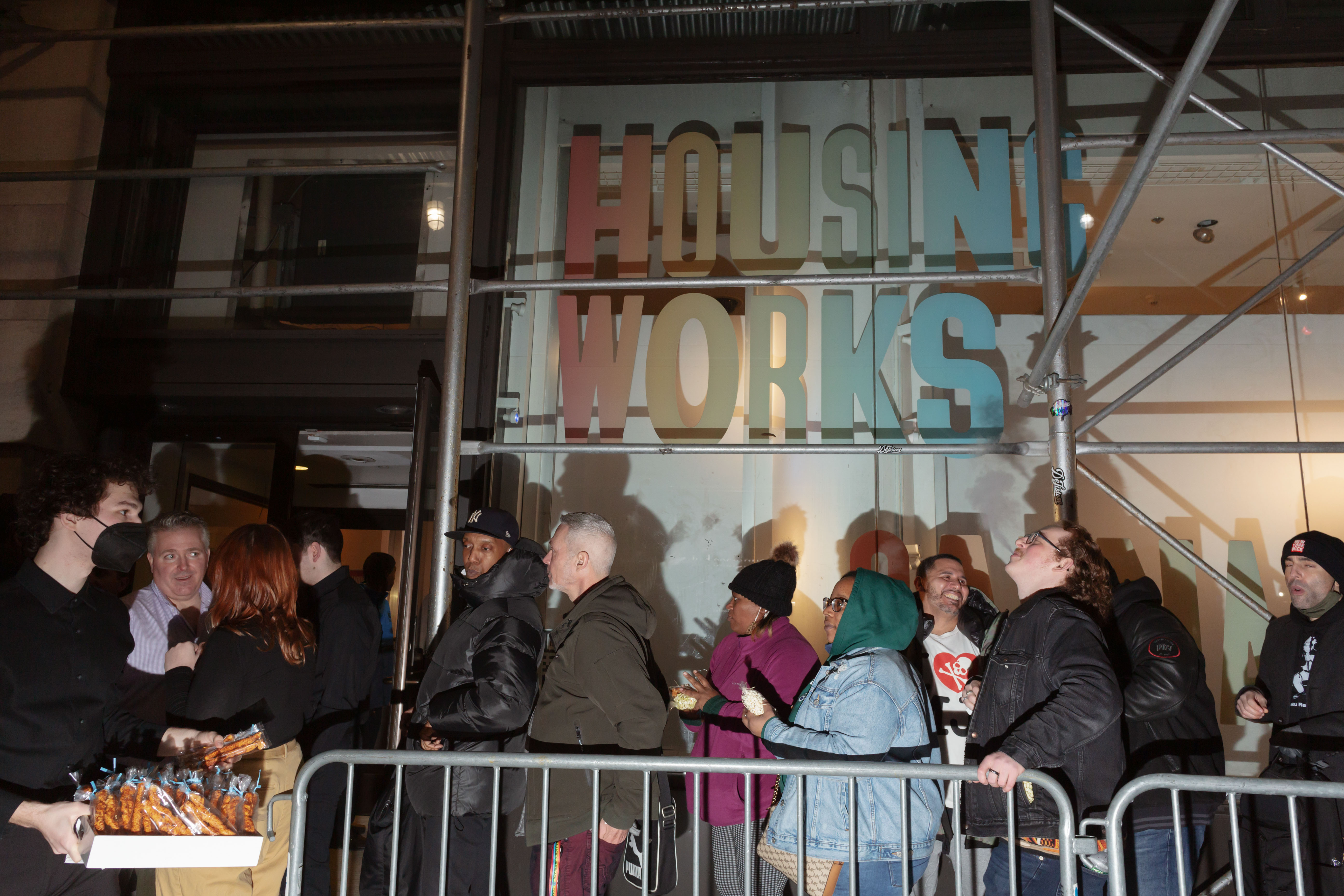 People line up in front of Housing Works, with an attendant passing out snacks.