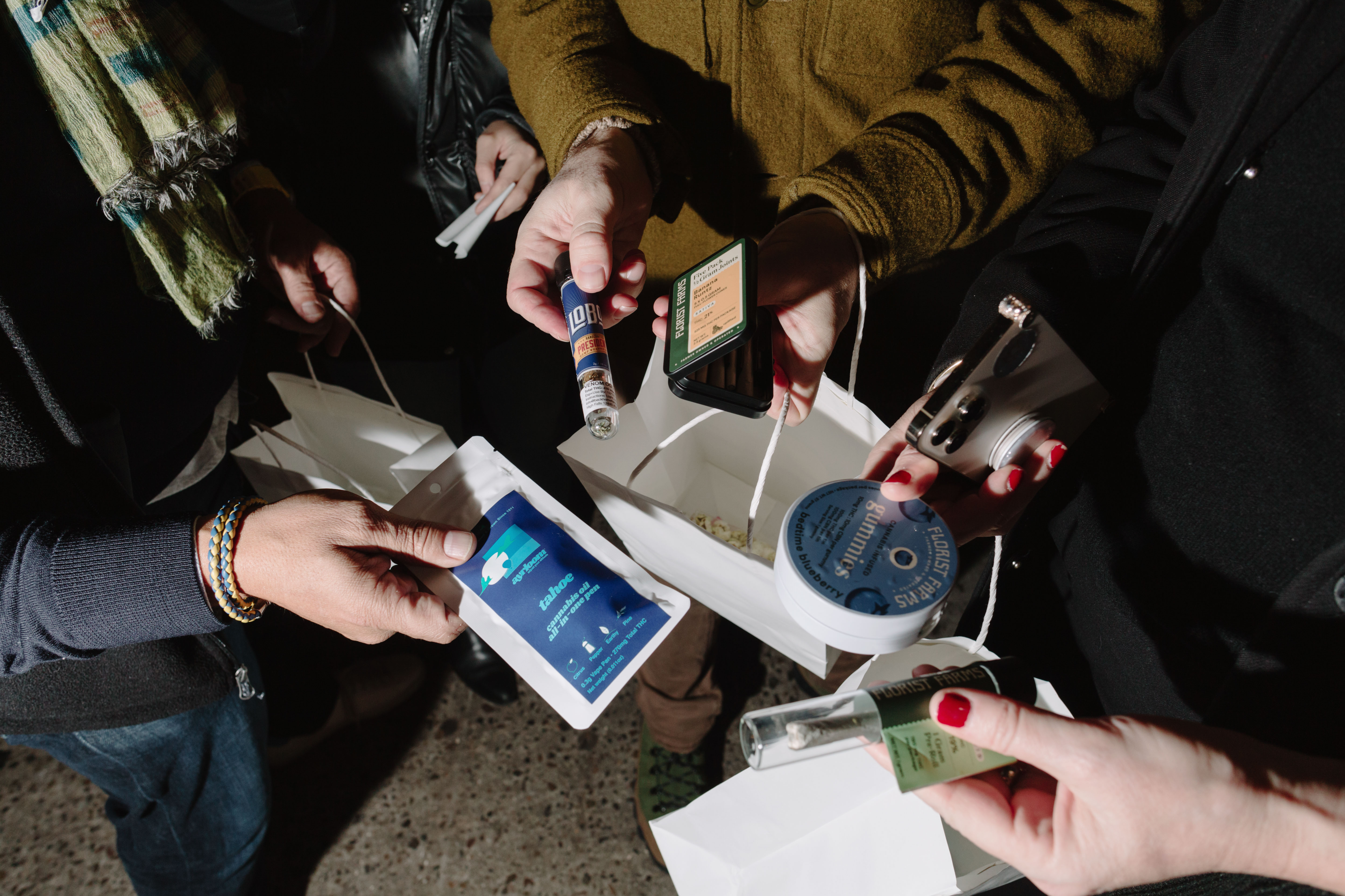 Customers hold out their their purchases from the dispensary, only their hands and products are seen.