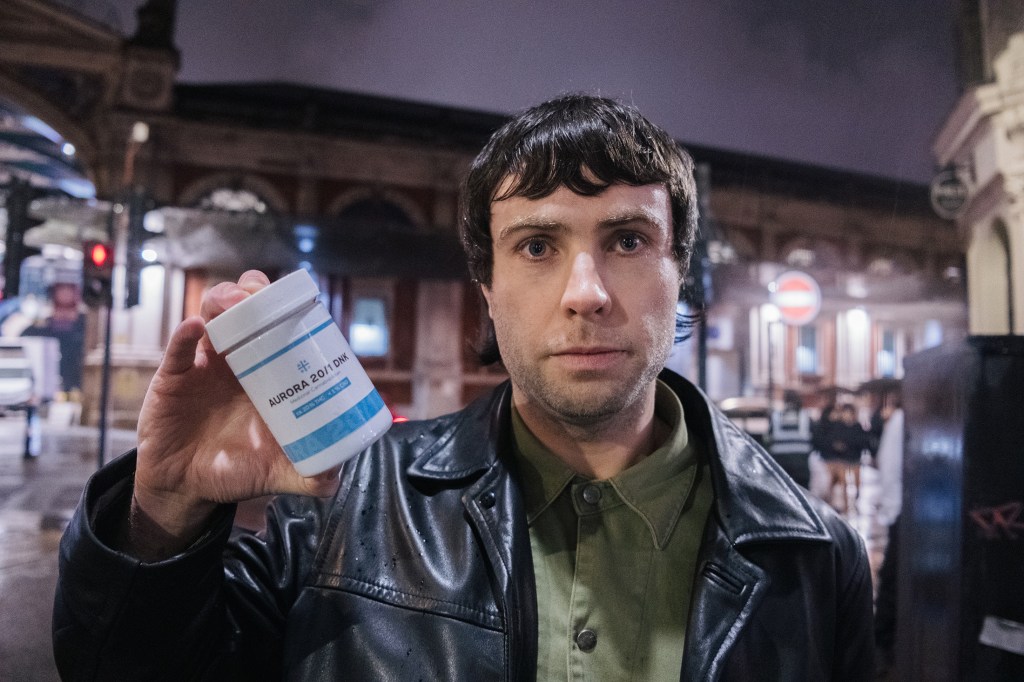 A man in leather jacket holds up prescription bottle of medical cannabis