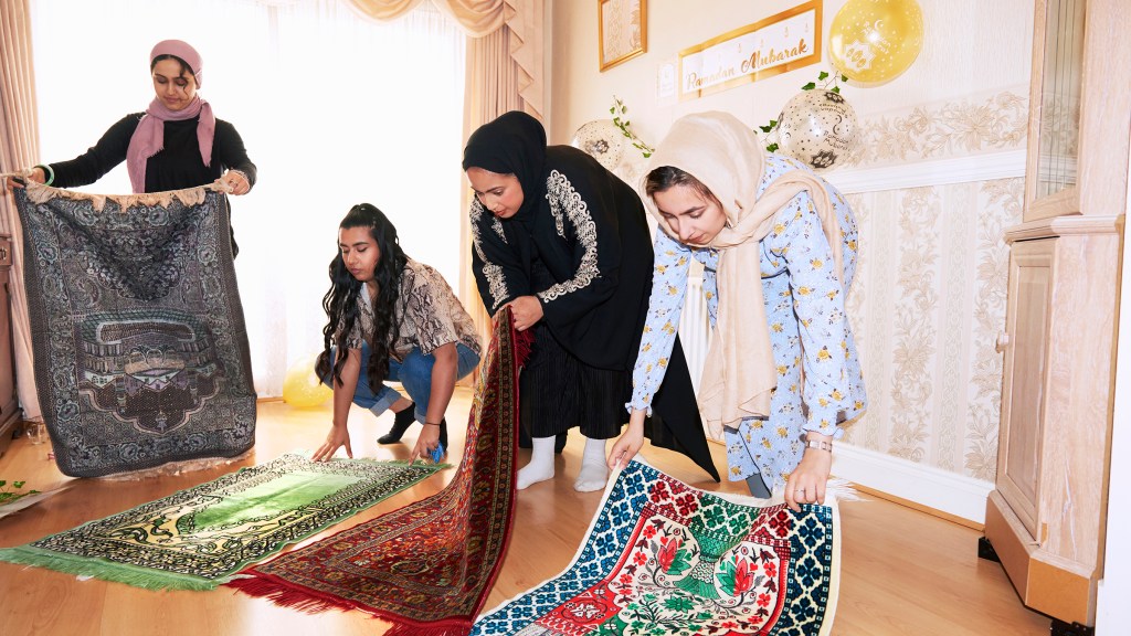 Foto von drei jungen Frauen, die Gebetsteppiche hinlegen, die Entscheidung ob und wie man Ramadan feiert, ist für die Autorin über die Jahre immer wieder schwierig gewesen.