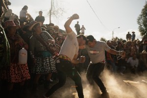 Takanakuy, Peru – two men caught mid-fight in front of a cheering crowd, their heads touching, their arms swinging, and a cloud of dust surrounding them.