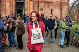 Ein Mann mit roten Haaren und roter Jacke steht vor einer Kirche