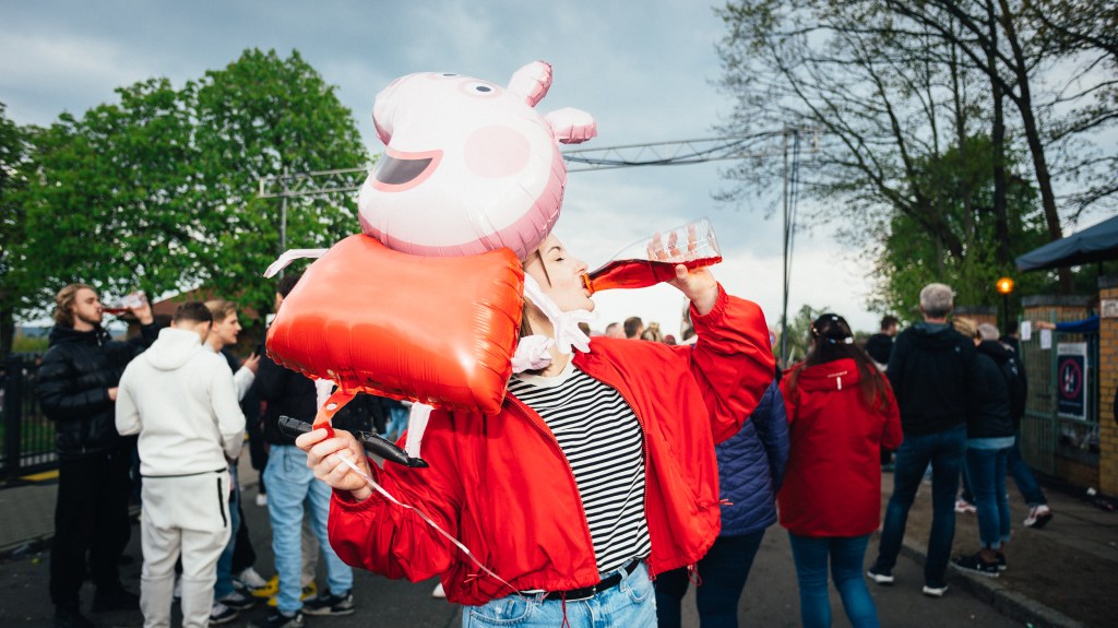 Die Autorin trink beim Baumblütenfest Wein und hält einen Luftballon