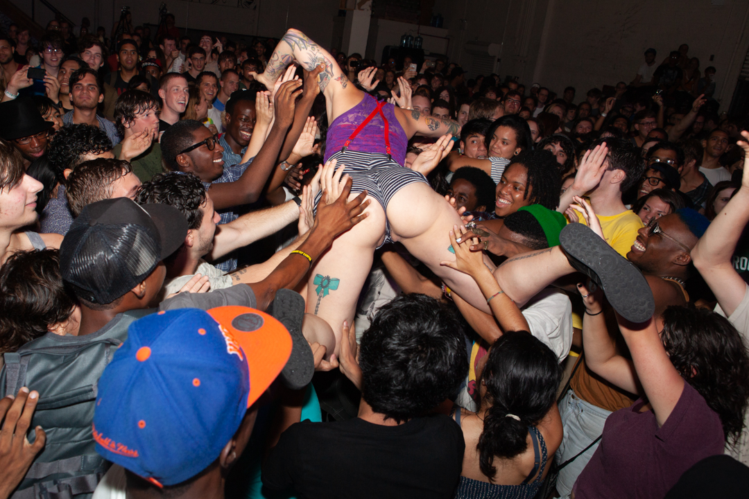 A woman crowdsurfing on top of a smiling crowd in Williamsburg, Brooklyn, NY, 2011.