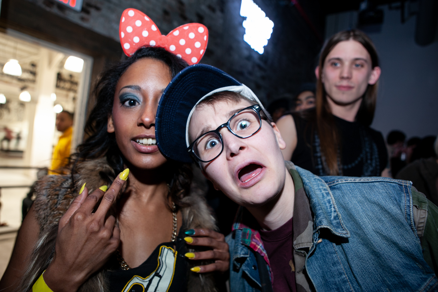 A woman in Minnie Mouse ears and a man in glasses look at camera