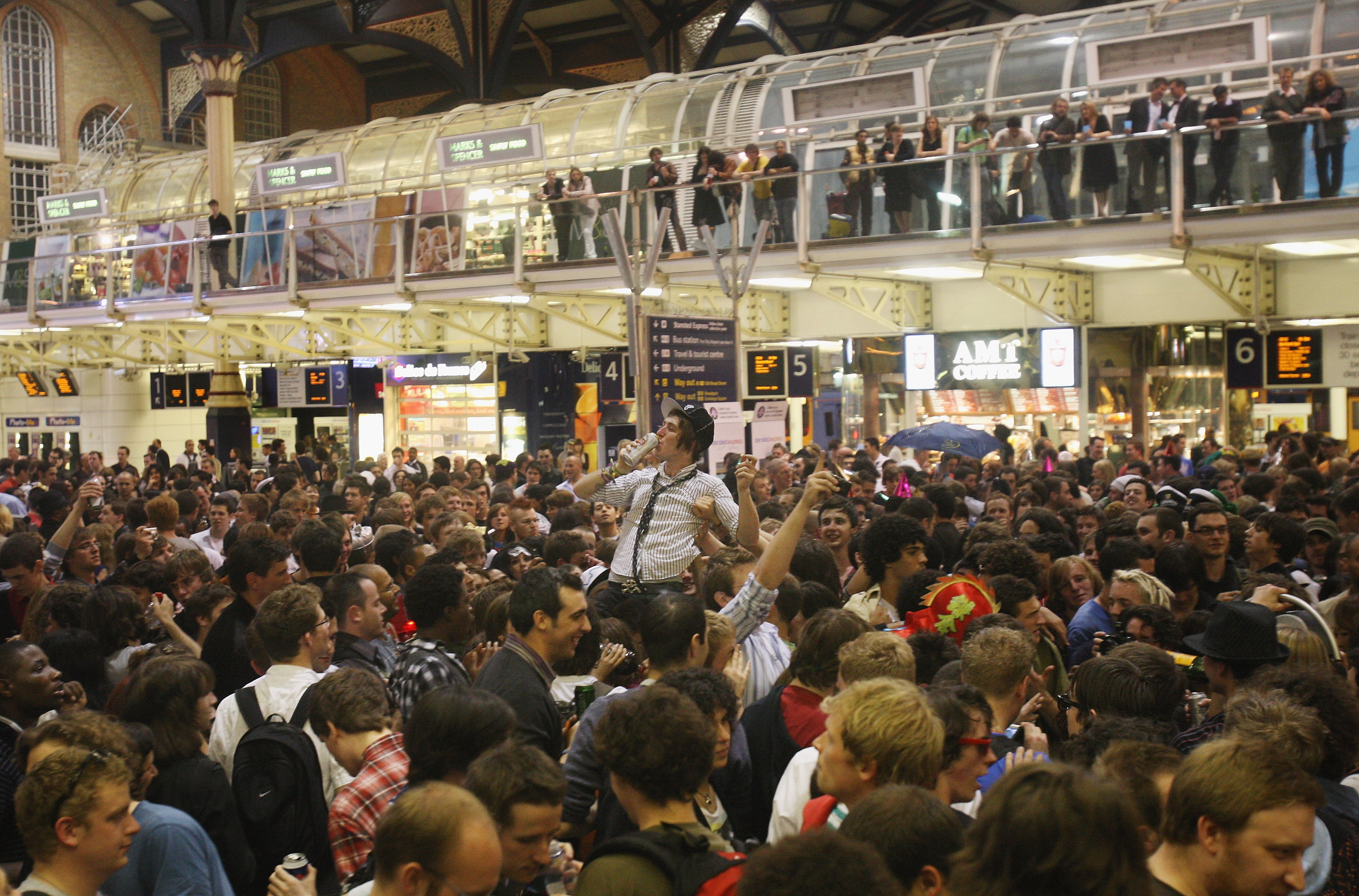 A photo of a huge crowd at Liverpool Street station drinking beers in costumes, having a party.