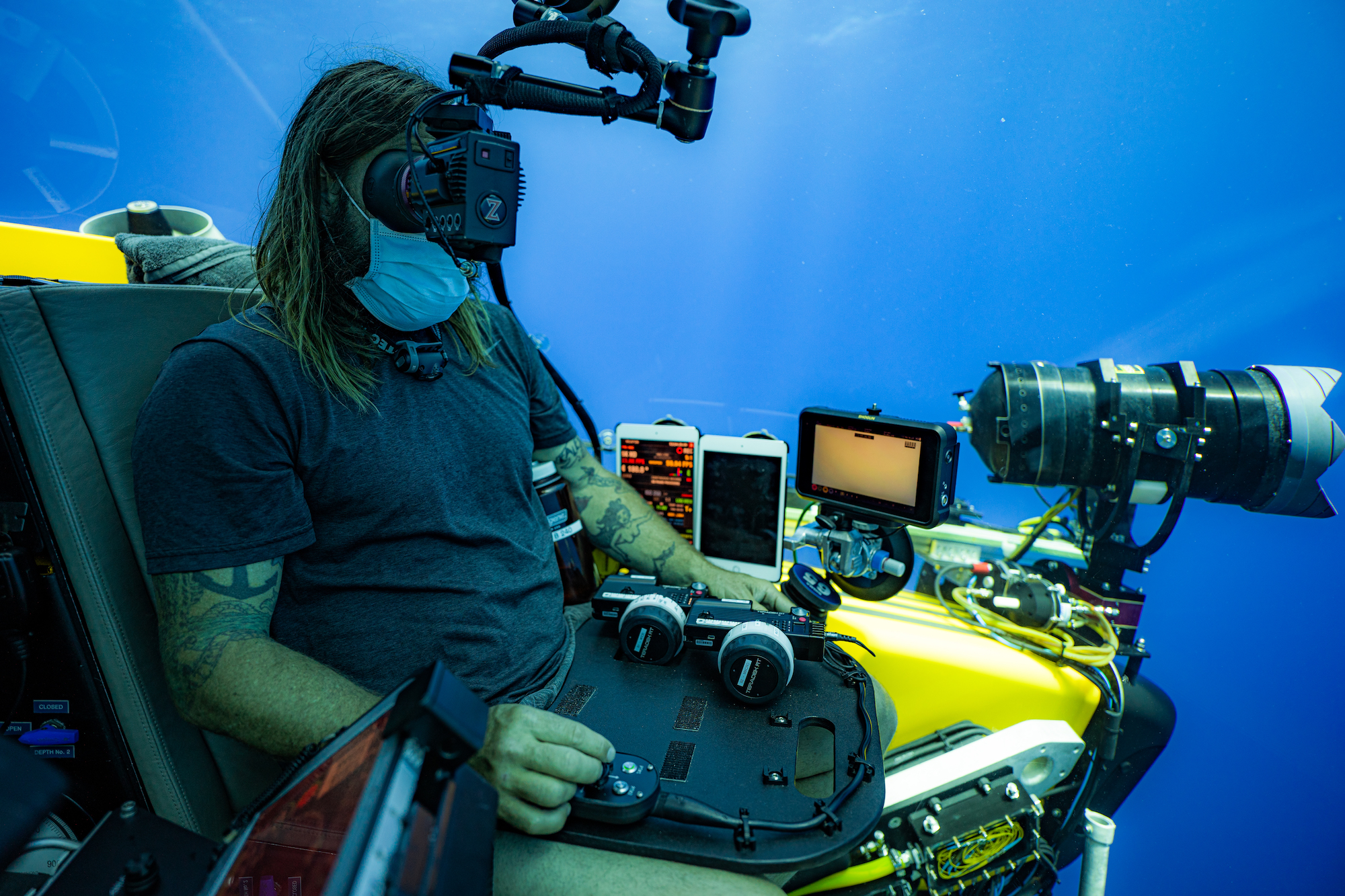 A man in a submersible surrounded by equipment