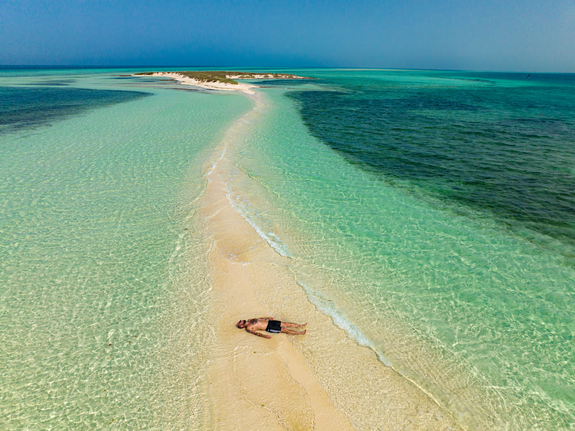 A man lying on white sand in ocean