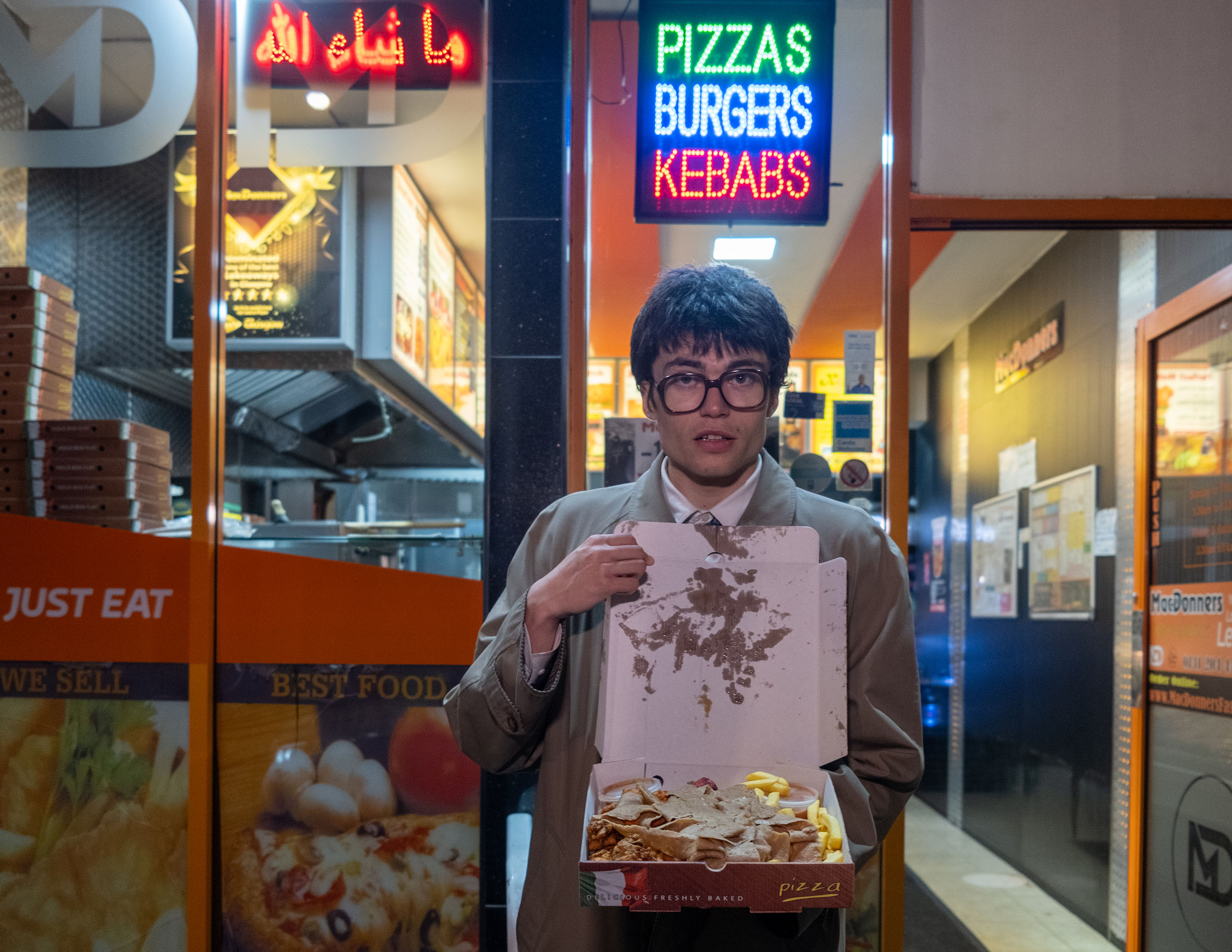 Man in glasses holding up a munchy box in Glasgow, Scotland