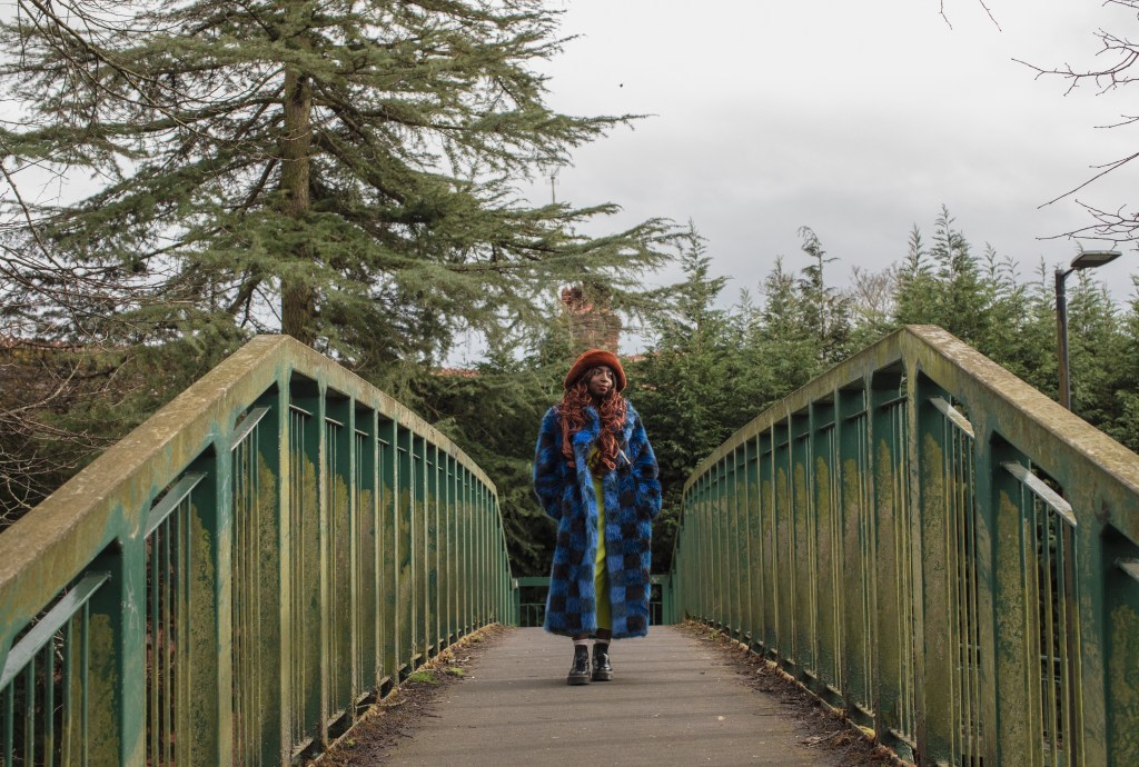 Manchester, UK: Kemi Alemoru in a blue fur coat on a bridge