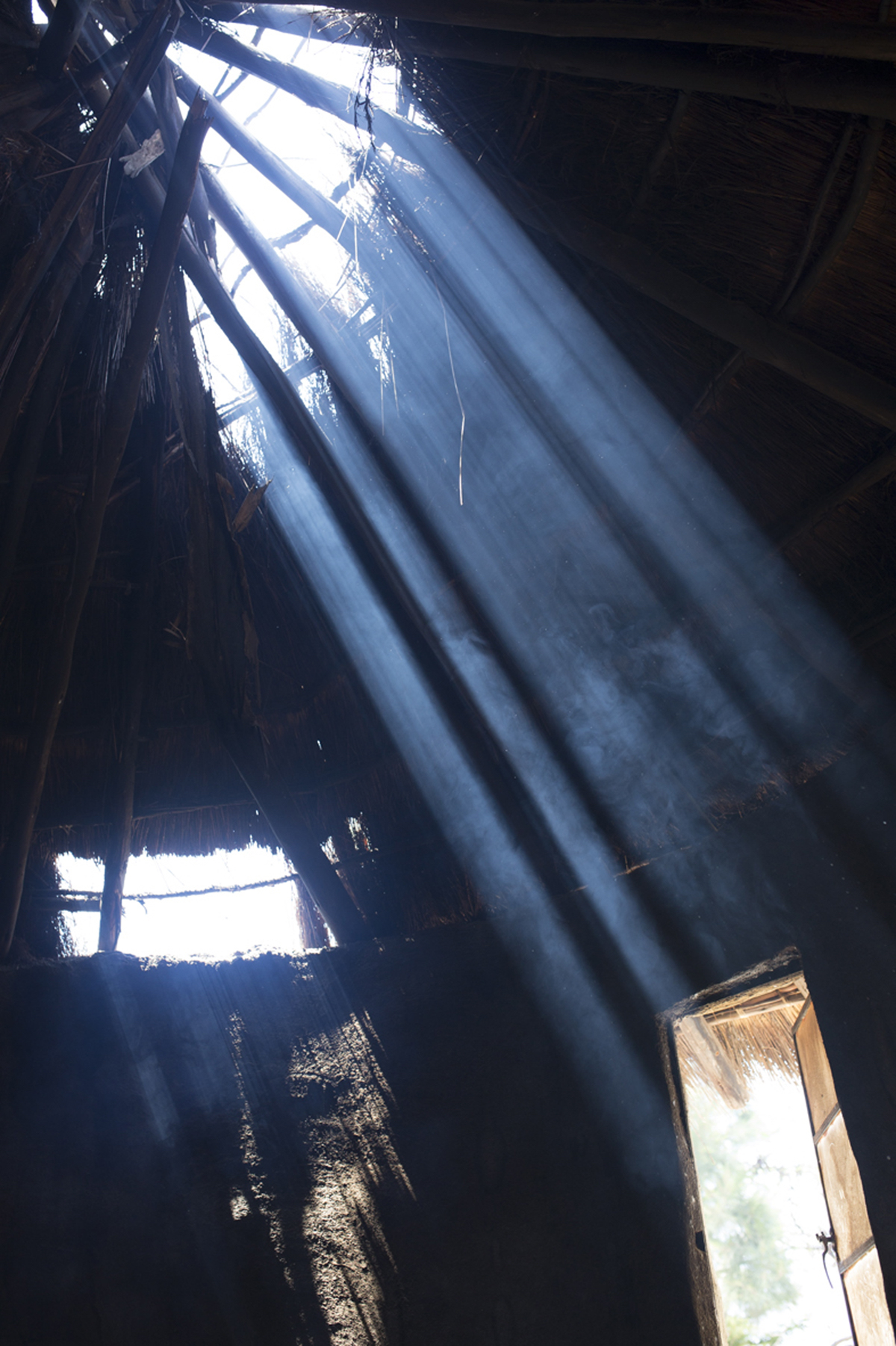 Giya Makondo-Wills, “They Came From The Water While The World Watched” – a hut with a hole in the straw roof from which sunlight is pouring in