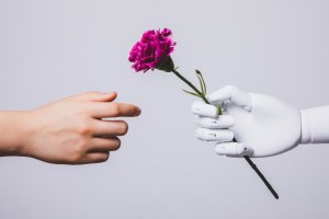 a robot hand holding out a flower to a human hand