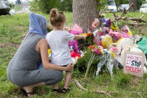 Families pay their respects on June 8, 2021, at a makeshift memorial near the site where a man driving a pickup truck struck and killed four members of a Muslim family in London, Ontario, Canada.